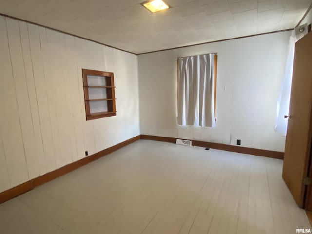 empty room featuring visible vents, baseboards, and wood finished floors