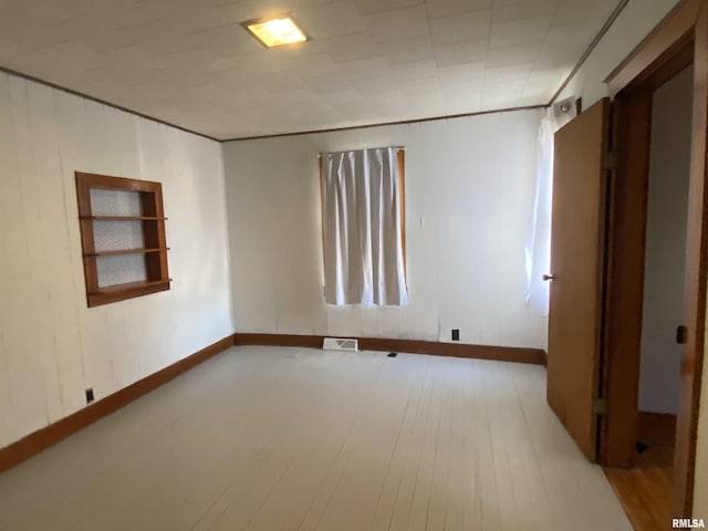 empty room featuring baseboards, visible vents, and wood finished floors