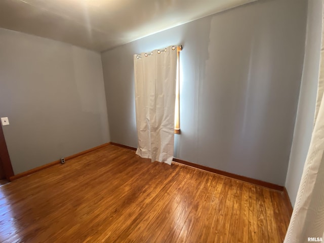 spare room featuring baseboards and hardwood / wood-style flooring