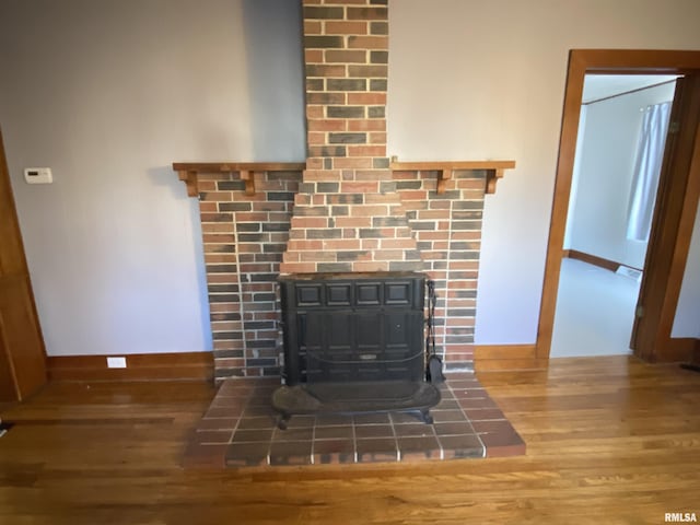 details featuring a wood stove, baseboards, and wood finished floors