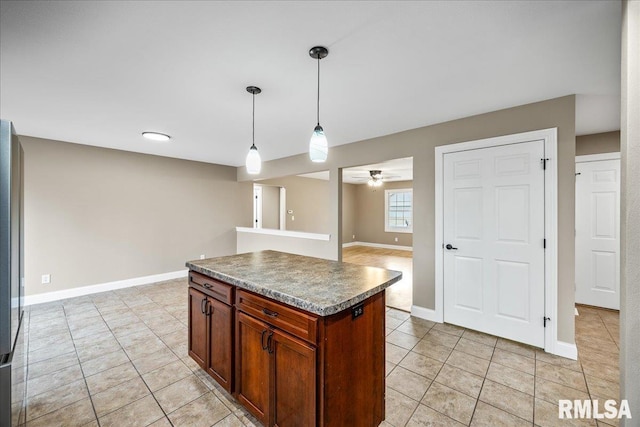 kitchen featuring light tile patterned floors, baseboards, decorative light fixtures, and a center island