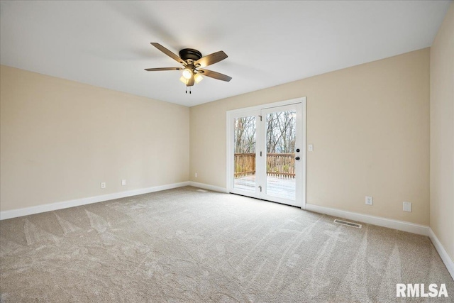 carpeted spare room with a ceiling fan, visible vents, and baseboards