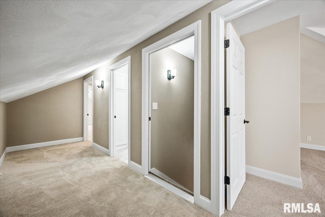 hall featuring vaulted ceiling, a textured ceiling, carpet flooring, and baseboards