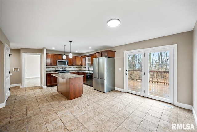 kitchen with appliances with stainless steel finishes, a kitchen island, hanging light fixtures, and baseboards