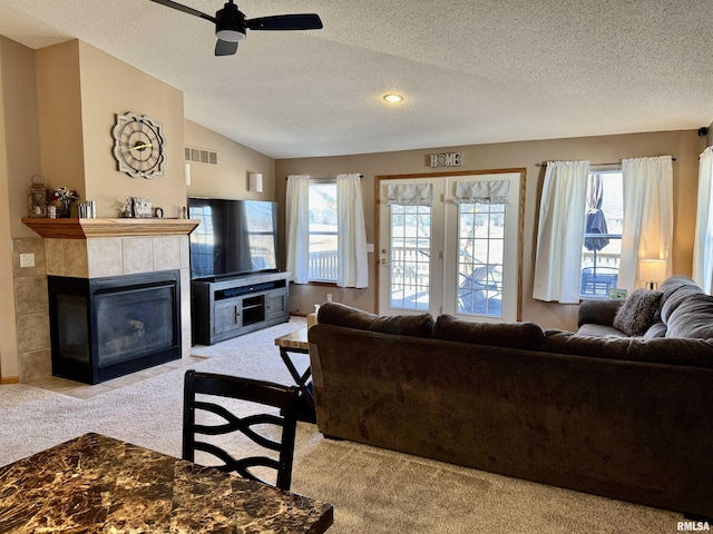 carpeted living room with lofted ceiling, a textured ceiling, a tile fireplace, and visible vents