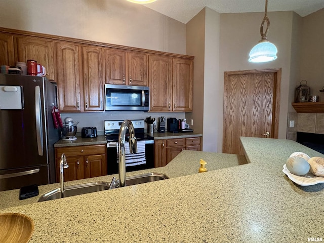 kitchen featuring appliances with stainless steel finishes, pendant lighting, brown cabinets, and light stone counters