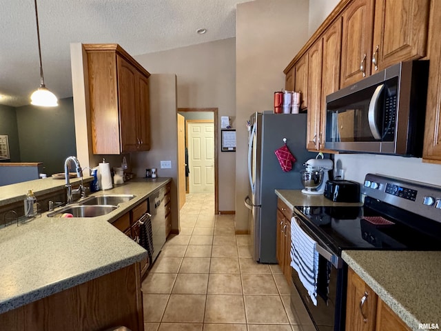 kitchen with light tile patterned floors, brown cabinetry, appliances with stainless steel finishes, a textured ceiling, and a sink