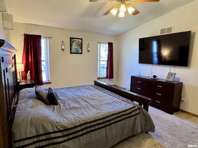 bedroom featuring lofted ceiling, ceiling fan, a textured ceiling, carpet flooring, and visible vents