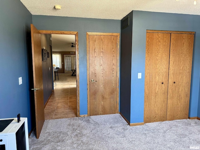 carpeted bedroom featuring baseboards, visible vents, a textured ceiling, and tile patterned floors