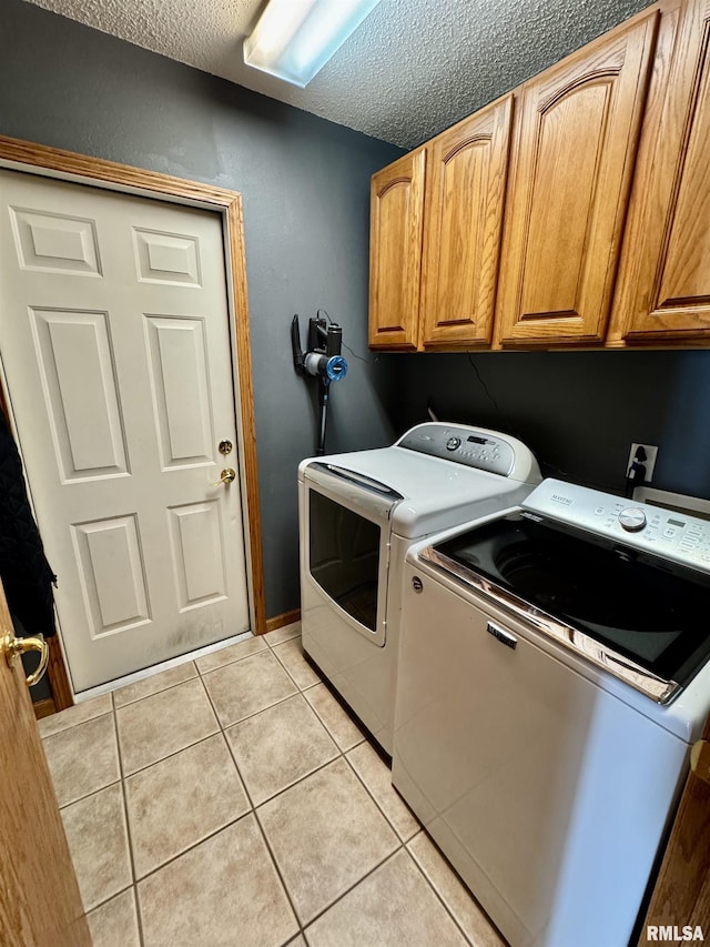 laundry room featuring cabinet space, independent washer and dryer, a textured ceiling, and light tile patterned floors