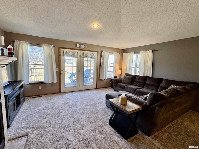 carpeted living room featuring a textured ceiling, visible vents, and baseboards