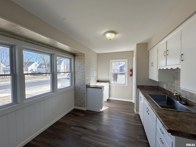 kitchen with a sink, dark countertops, dark wood-style floors, and white cabinets