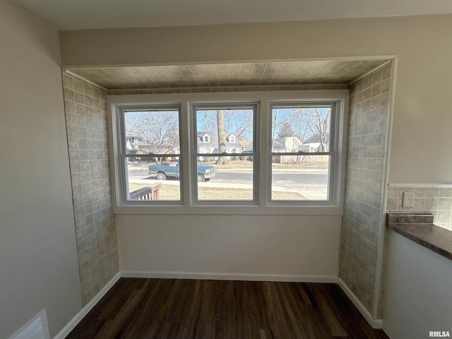 unfurnished room featuring dark wood-style floors, visible vents, and baseboards