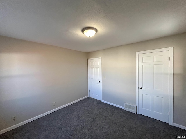 unfurnished room featuring baseboards, visible vents, and dark carpet