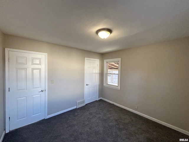 unfurnished bedroom featuring a closet, baseboards, visible vents, and dark carpet