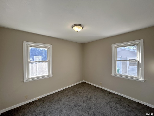 unfurnished room with dark colored carpet and baseboards