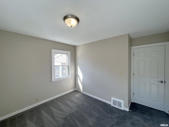 unfurnished room featuring baseboards, visible vents, and dark colored carpet