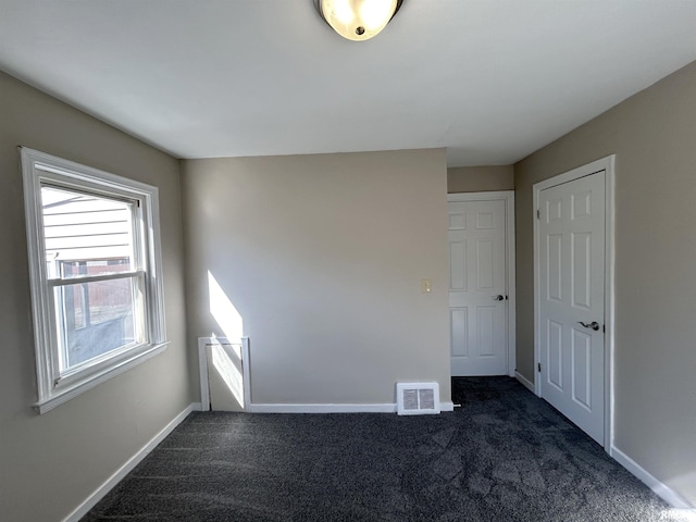 unfurnished room featuring baseboards, visible vents, and dark colored carpet