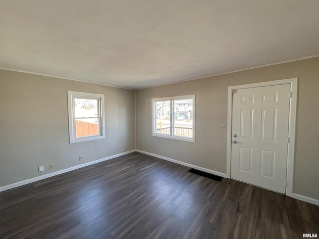 spare room featuring baseboards, ornamental molding, and dark wood-style flooring