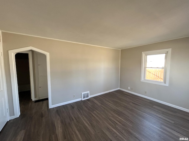 spare room with visible vents, baseboards, and dark wood finished floors