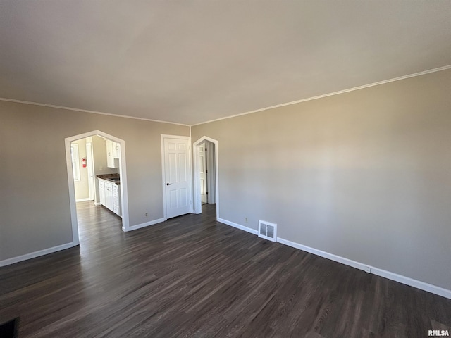 unfurnished room with visible vents, baseboards, dark wood-type flooring, and crown molding