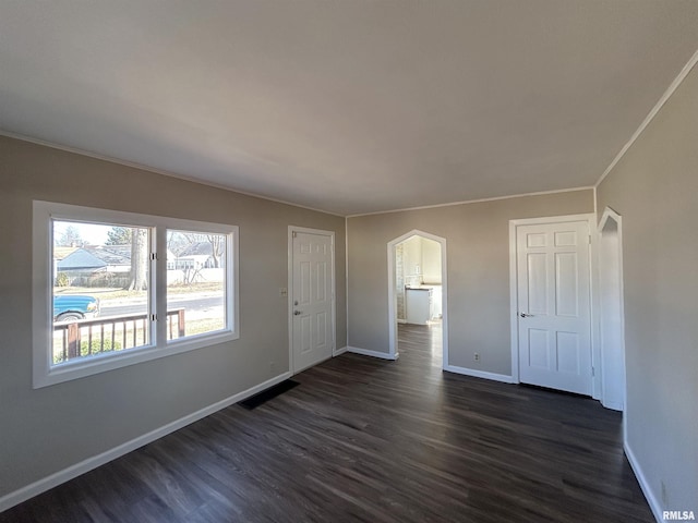 spare room with visible vents, baseboards, dark wood-style flooring, and ornamental molding