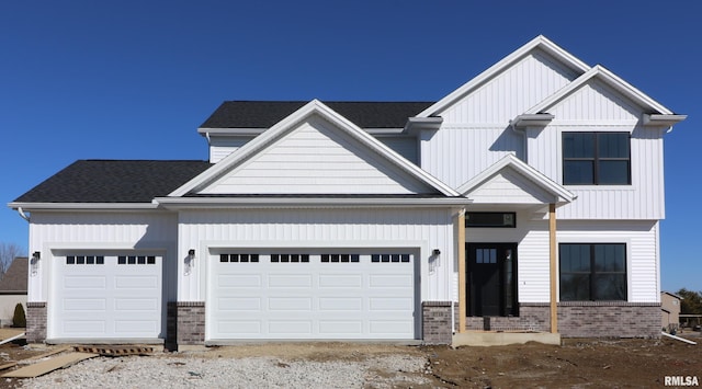 modern farmhouse featuring a garage, roof with shingles, brick siding, and board and batten siding