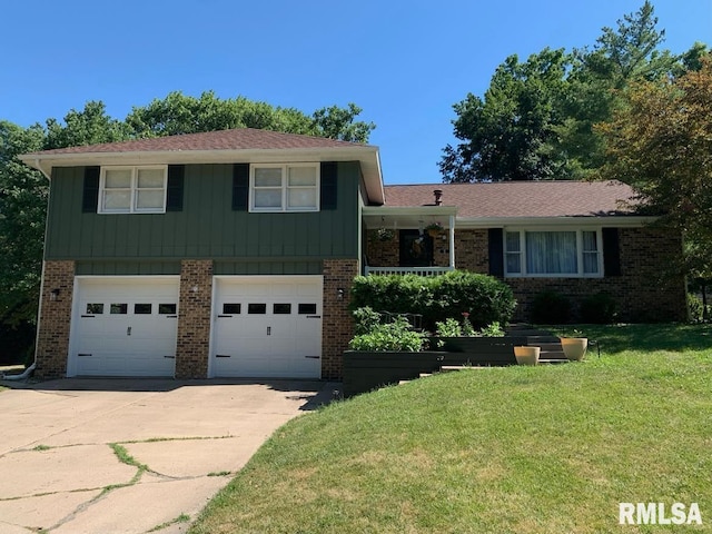 tri-level home with driveway, a garage, a front yard, and brick siding