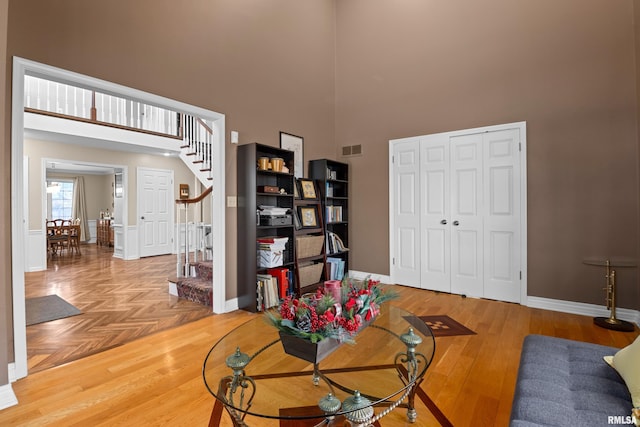 living room with baseboards, visible vents, a high ceiling, stairs, and parquet floors