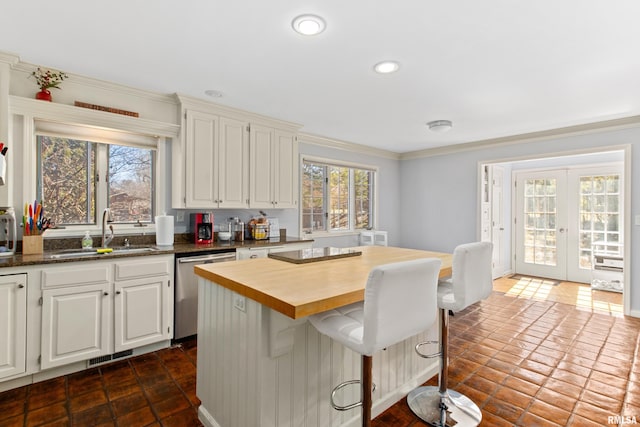 kitchen with visible vents, a sink, a center island, wooden counters, and dishwasher