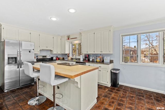 kitchen with baseboards, wooden counters, a sink, appliances with stainless steel finishes, and a center island