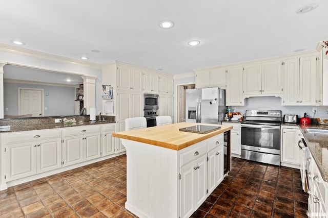 kitchen featuring a kitchen island, crown molding, recessed lighting, appliances with stainless steel finishes, and wood counters