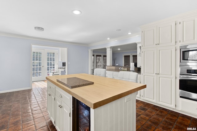 kitchen featuring ornamental molding, wine cooler, appliances with stainless steel finishes, white cabinetry, and butcher block counters