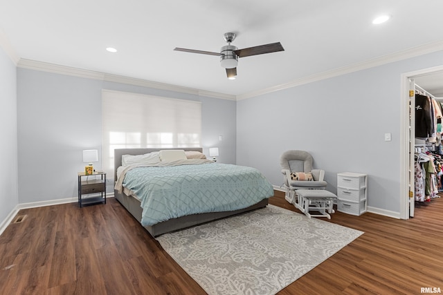 bedroom with a spacious closet, ornamental molding, baseboards, and wood finished floors