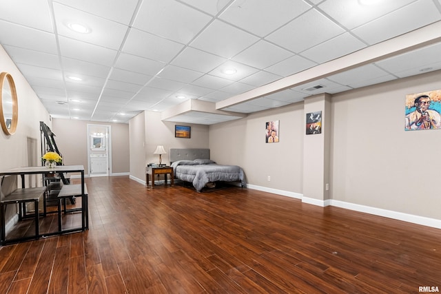 bedroom with visible vents, a paneled ceiling, baseboards, and wood finished floors