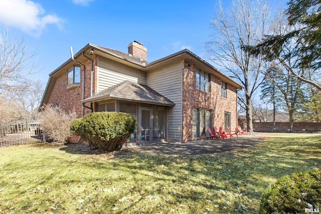 view of side of home featuring a yard, brick siding, a chimney, and fence