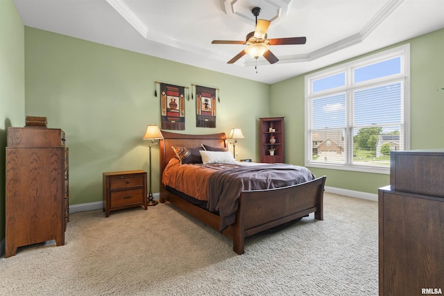 carpeted bedroom with a raised ceiling, ornamental molding, connected bathroom, ceiling fan, and baseboards