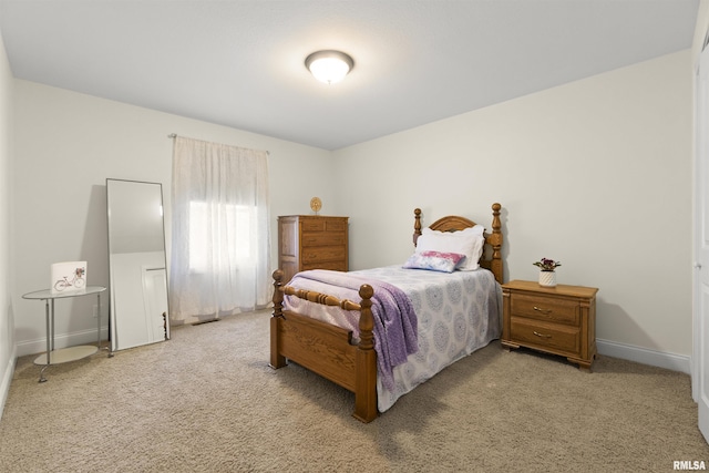 bedroom with baseboards, a closet, and light colored carpet