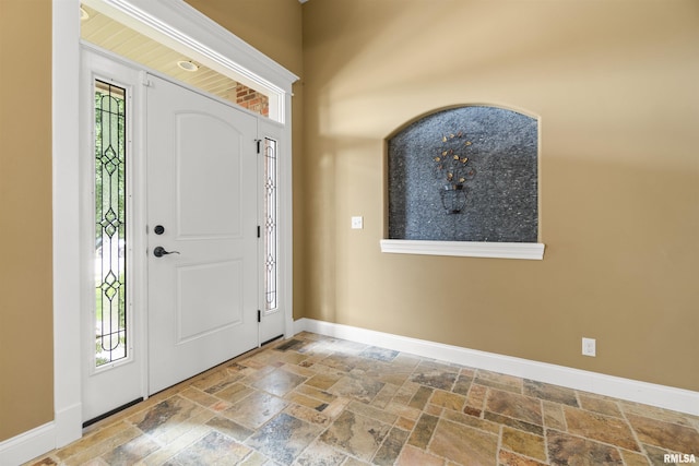 entryway with baseboards and stone tile floors