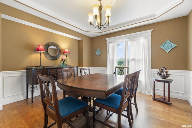 dining area featuring light wood finished floors, a chandelier, ornamental molding, and wainscoting