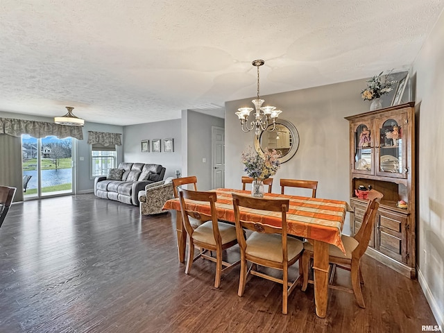 dining space featuring baseboards, a textured ceiling, dark wood-type flooring, and an inviting chandelier