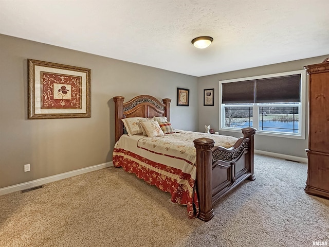 bedroom featuring carpet flooring, visible vents, baseboards, and a textured ceiling