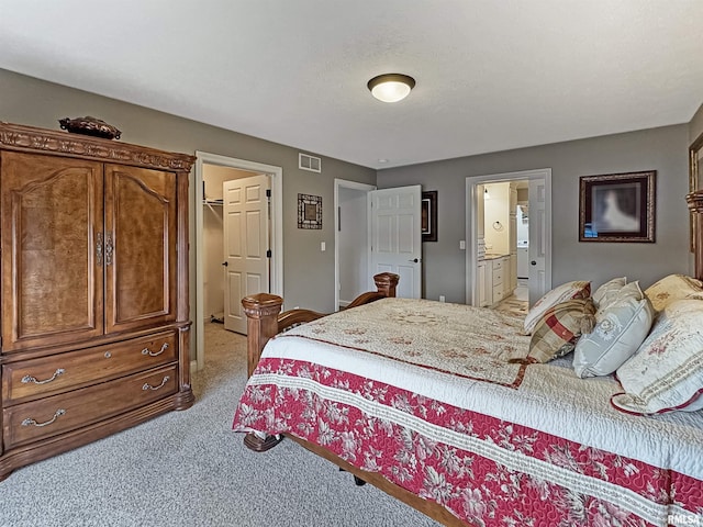 bedroom featuring light carpet, visible vents, connected bathroom, and a walk in closet