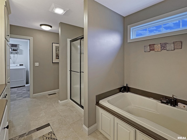 bathroom featuring a bath, a stall shower, washer / clothes dryer, and baseboards