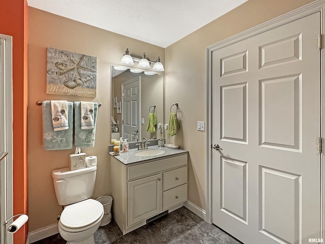 bathroom featuring toilet, a textured ceiling, vanity, and baseboards