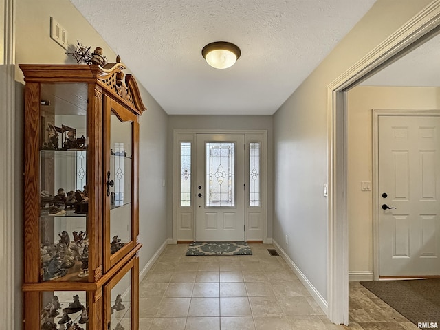 entrance foyer with light tile patterned floors, visible vents, baseboards, and a textured ceiling