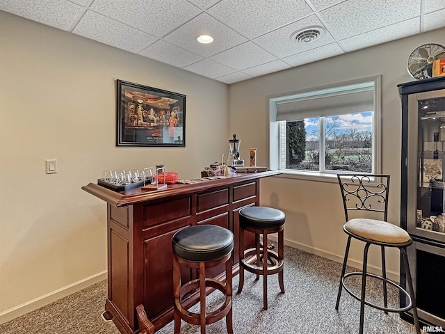 bar with visible vents, baseboards, carpet, a paneled ceiling, and a dry bar