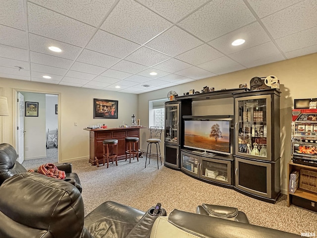 carpeted living area with recessed lighting, a bar, a paneled ceiling, and baseboards