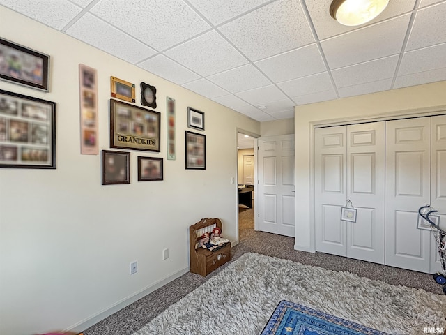 carpeted bedroom featuring a closet, a paneled ceiling, and baseboards