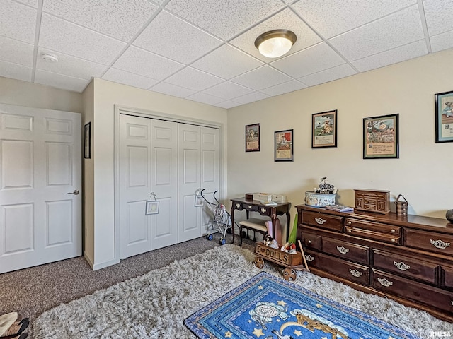 carpeted bedroom with a drop ceiling and a closet